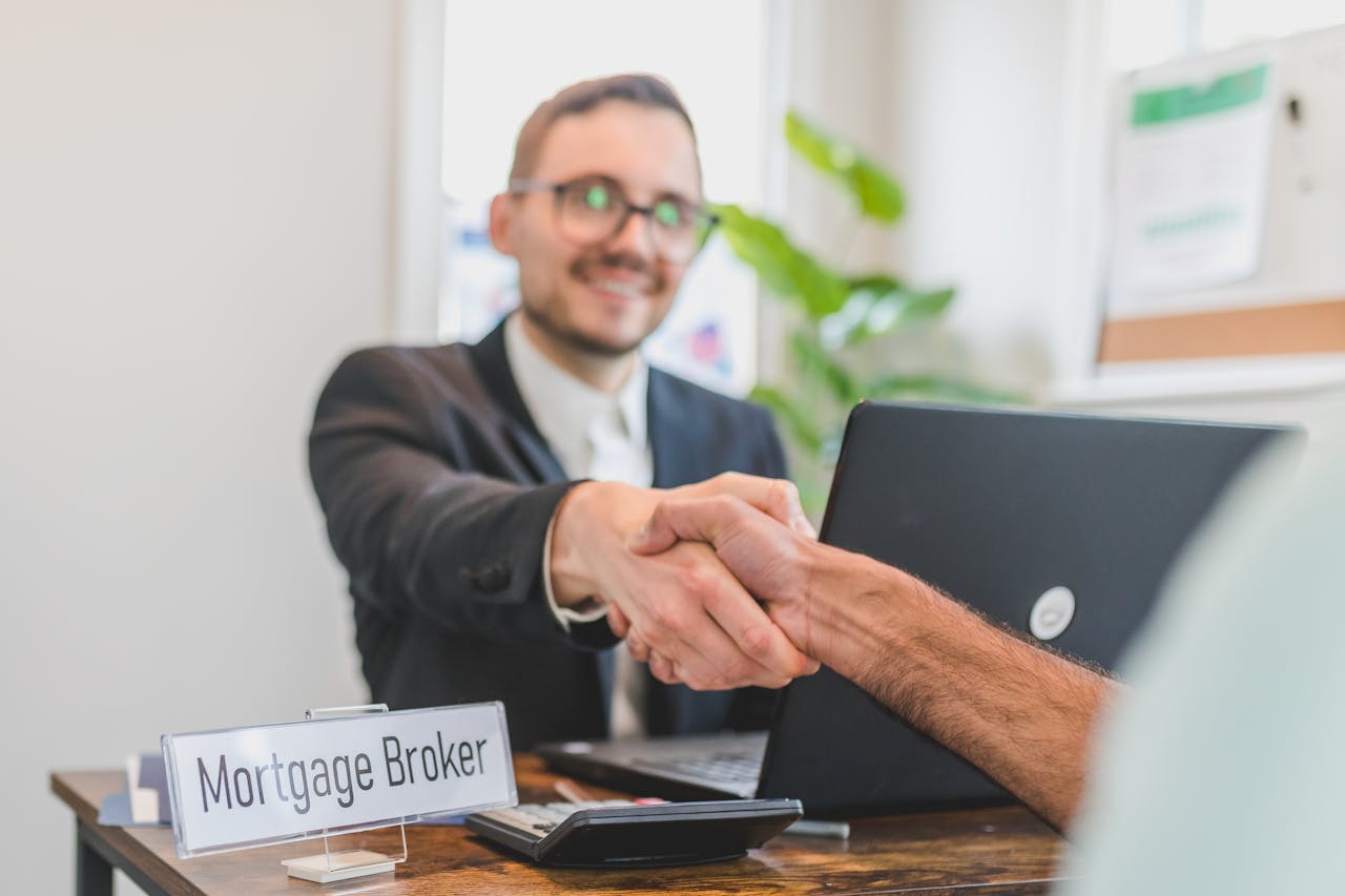 heros-img Mortgage broker and client sealing a deal with a handshake in a bright, modern office.